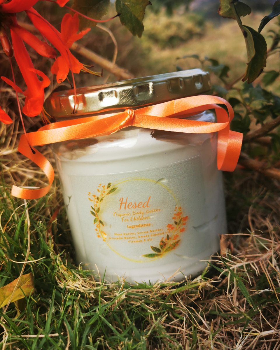 Children's unscented body butter with an orange ribbon, on grass